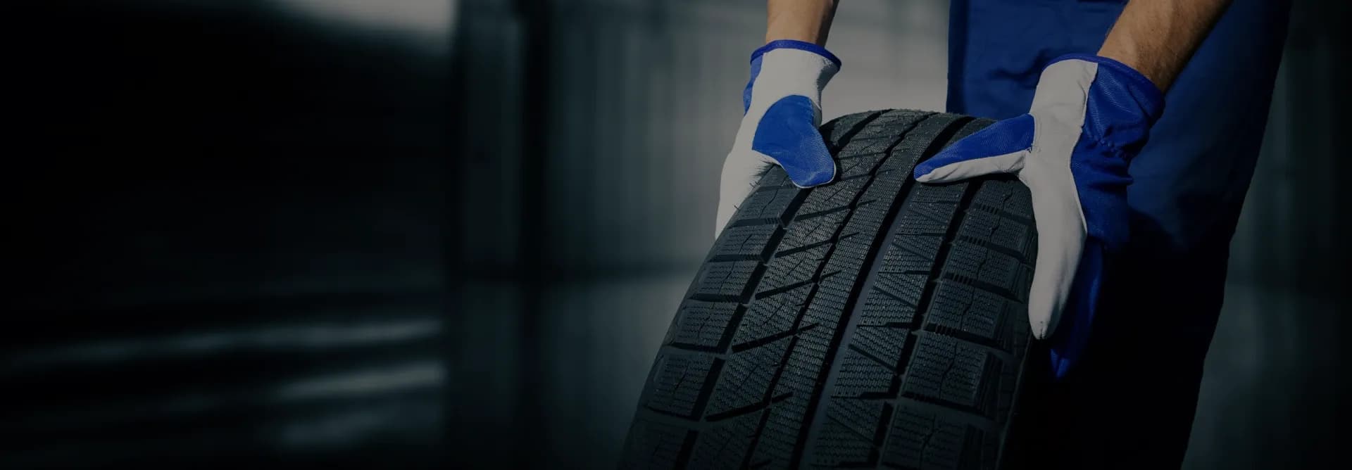 Tyre fitter at Braefel Garage rolling a winter tyre